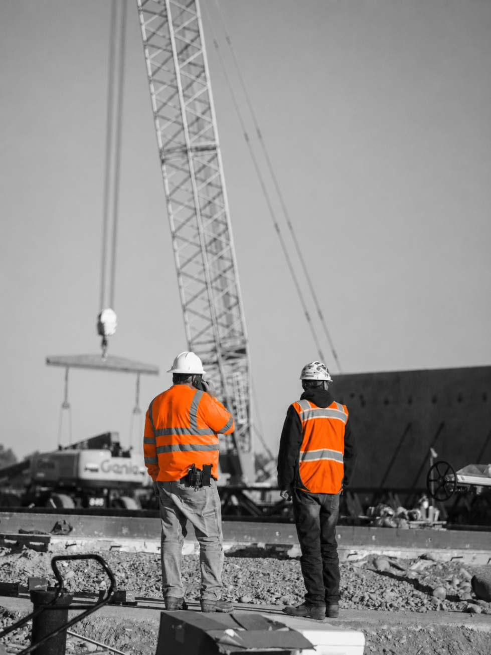 Two Relay Labour workers standing beneath a crane and Genie machinery on site